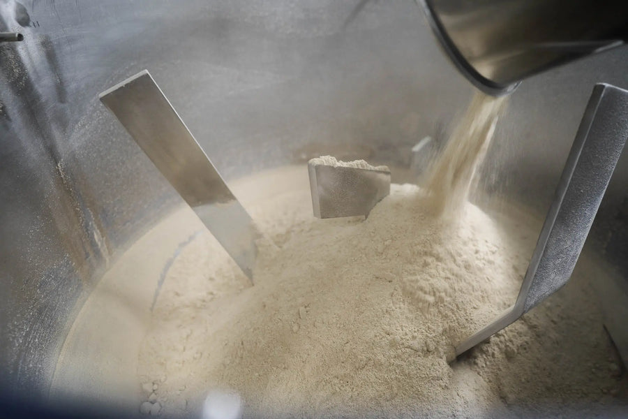 Kava powder being folded together by paddles inside a stainless blending vessel